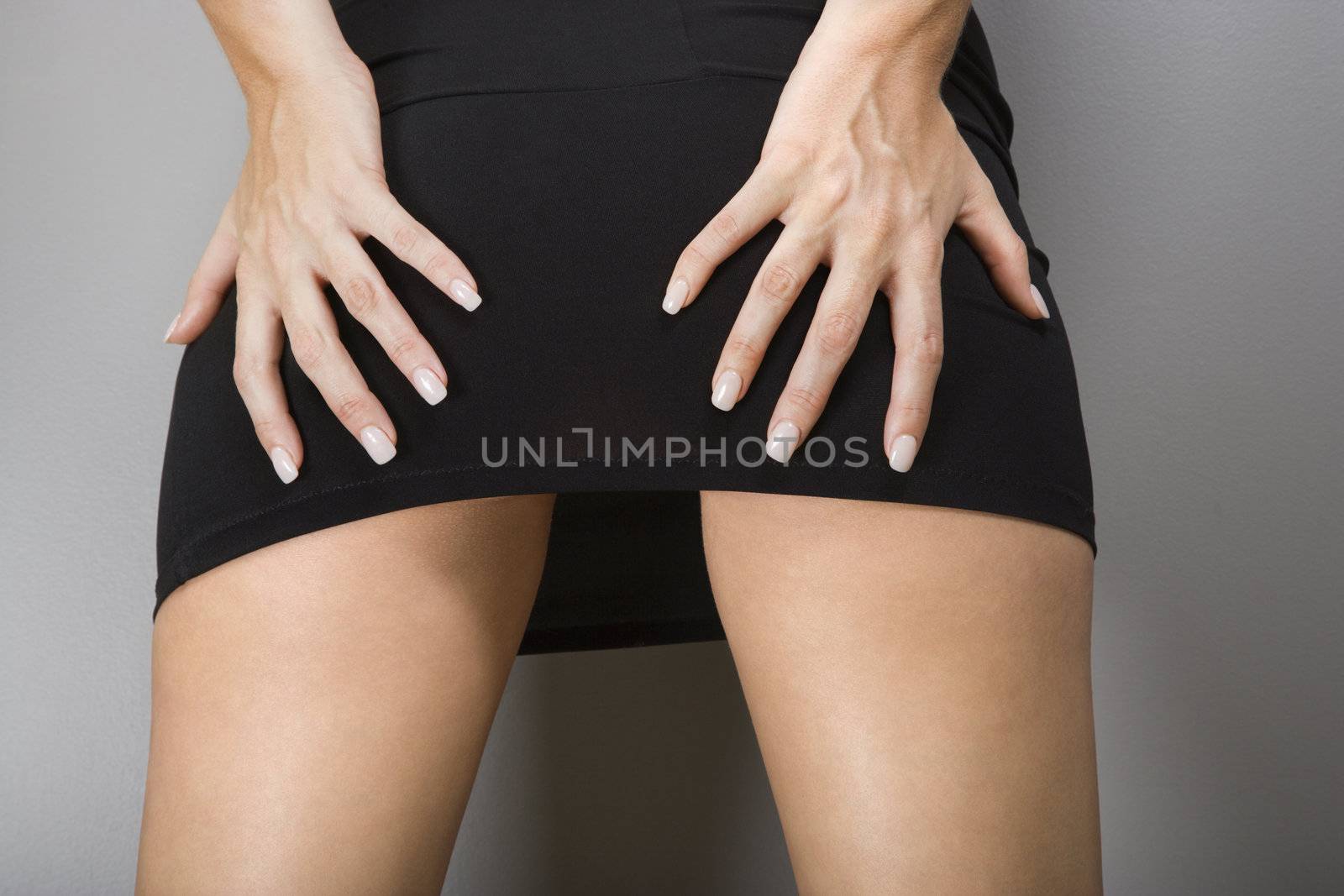 Close up of Caucasian female wearing miniskirt with hands on buttocks.