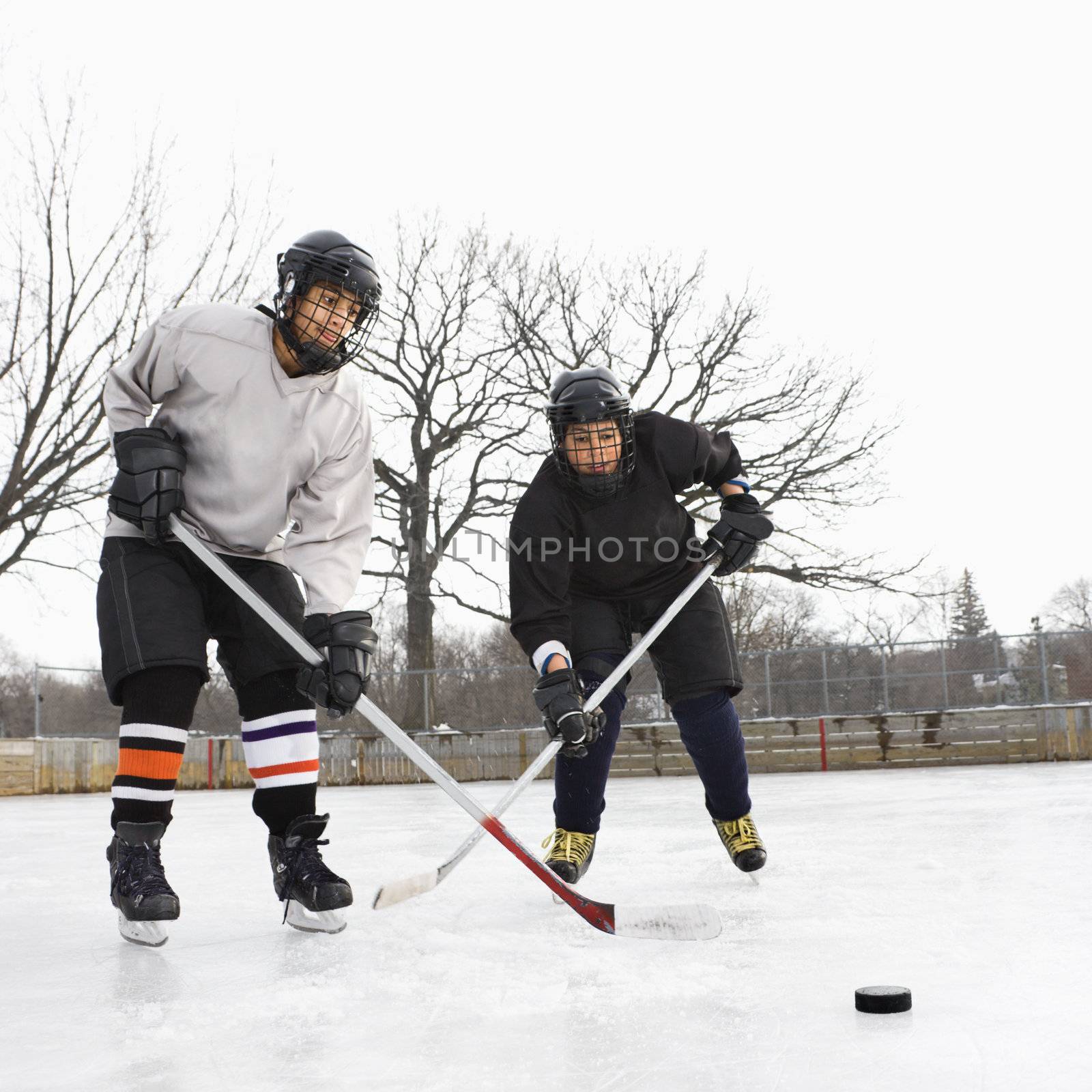 Boys playing ice hockey. by iofoto