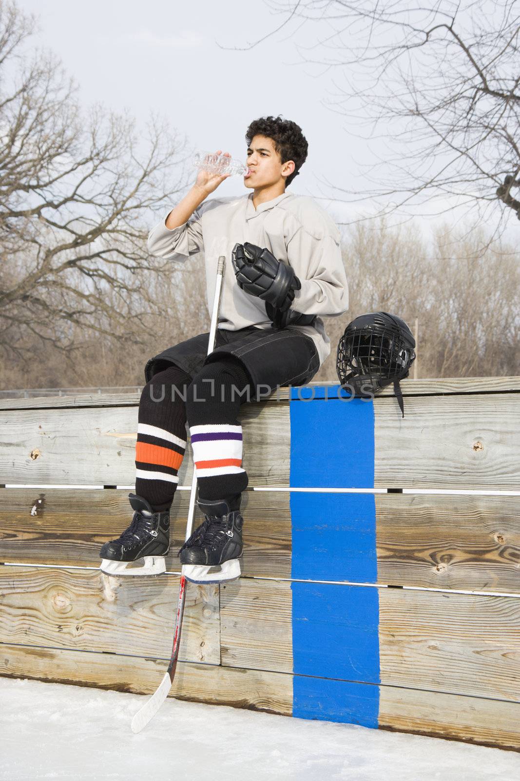 Hockey boy drinking water. by iofoto