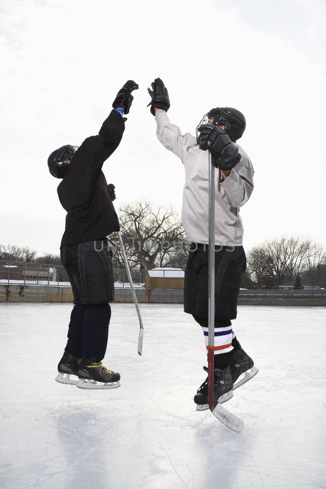 Hockey players high fiving. by iofoto