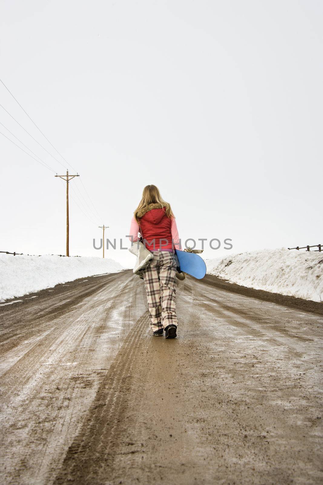 Woman carrying snowboard. by iofoto