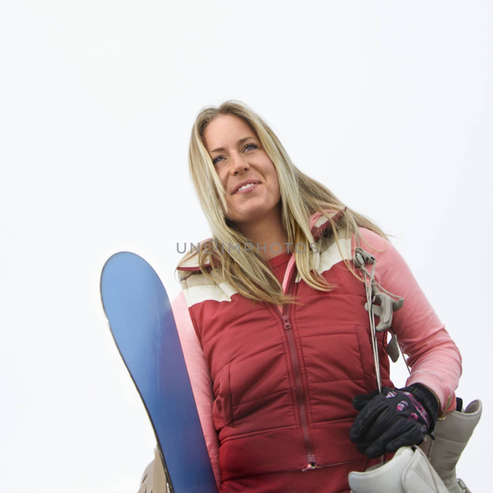 Young woman holding snowboard and boots.