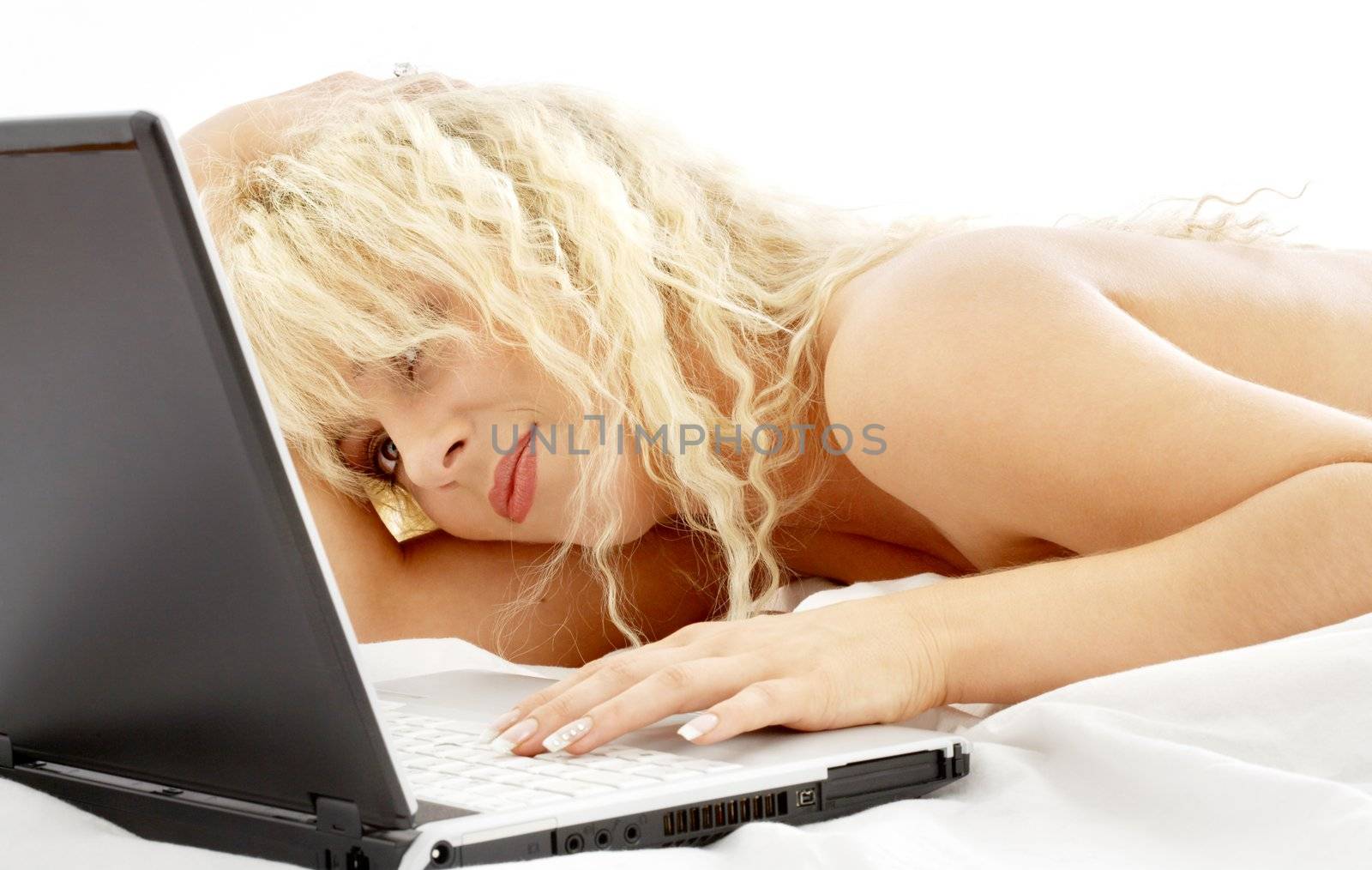 portrait of blond laying in bed with laptop by dolgachov