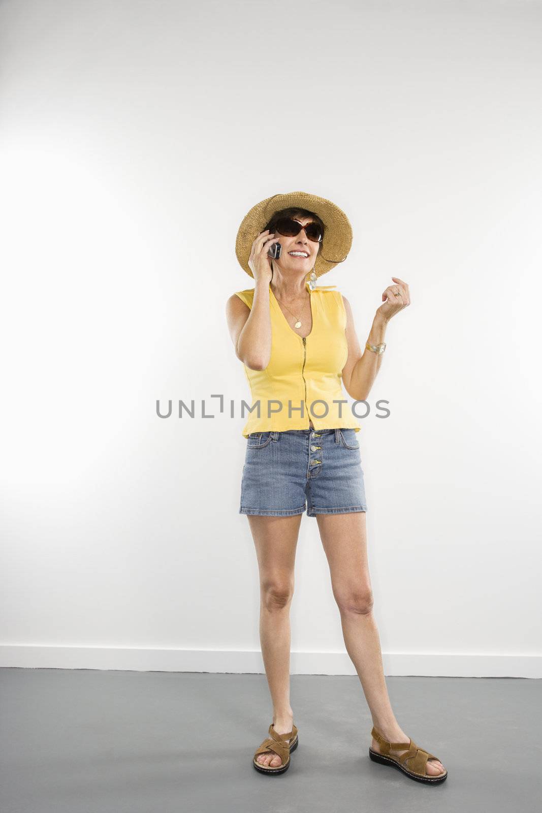 Portrait of pretty Caucasian woman in summer attire talking on cellphone.