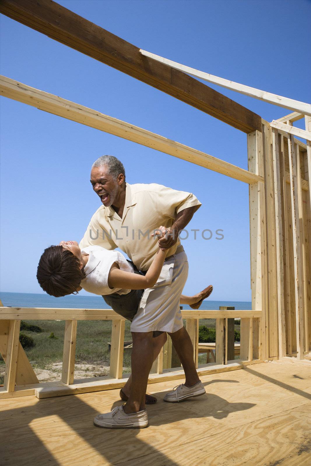 African American middle aged couple dancing in new home construction at beach.