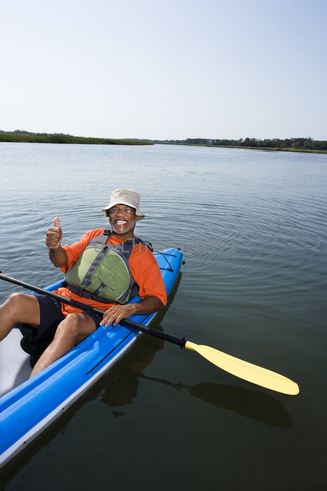 African American middle-aged man smiling and giving thumbs up gesure in kayak.