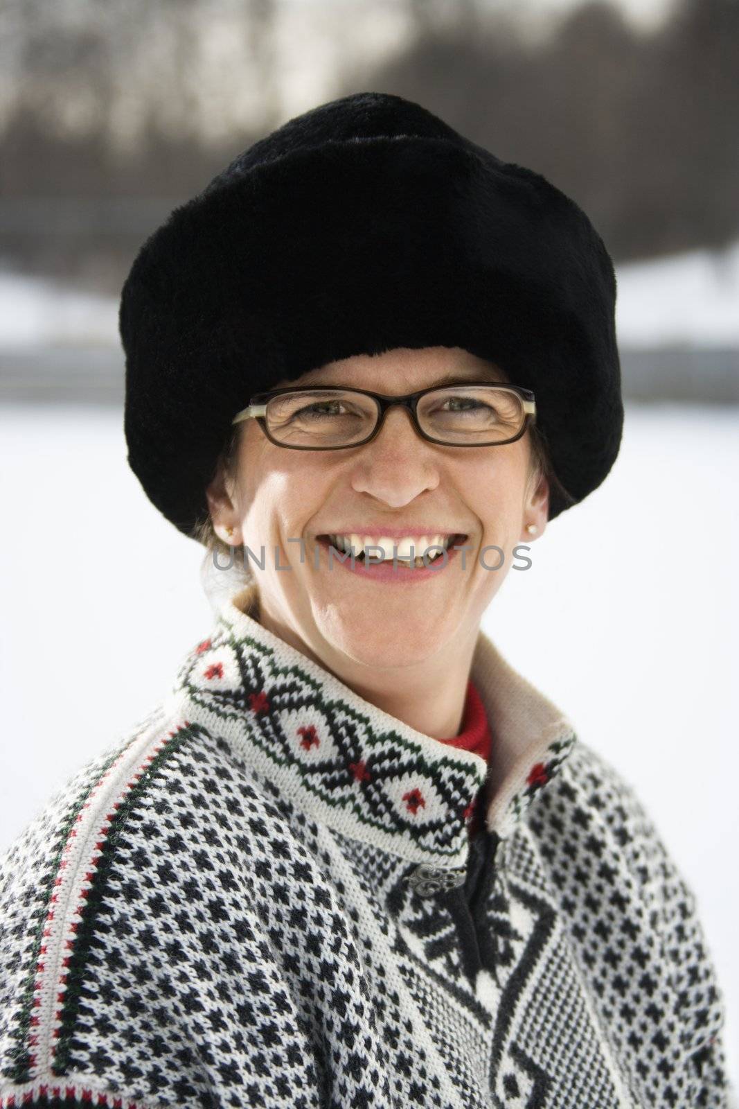 Portrait of Caucasian middle aged woman wearing sweater and black winter hat smiling at viewer.
