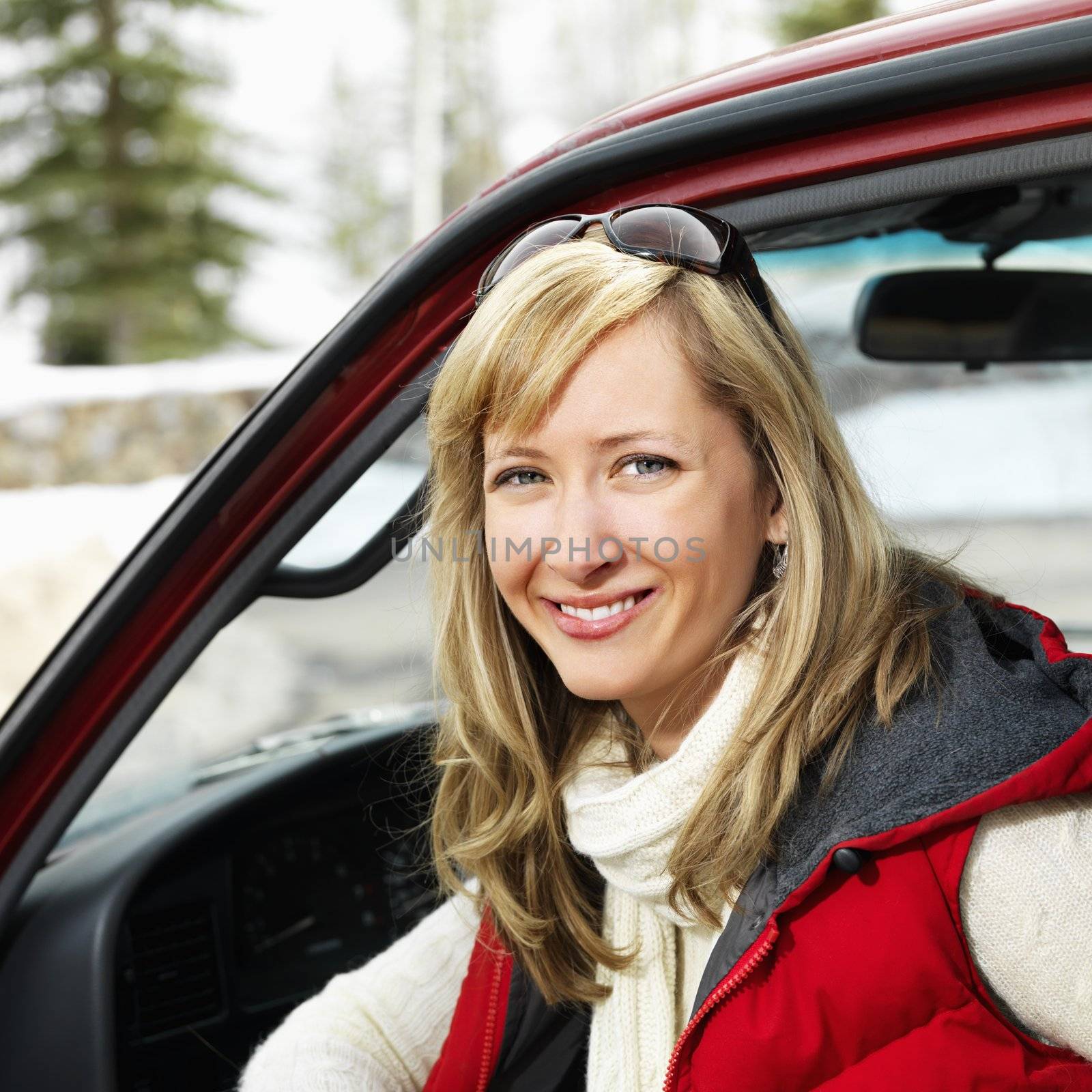 Pretty woman sitting in vehicle wearing winter clothes in rural snowy Colorado smiling.