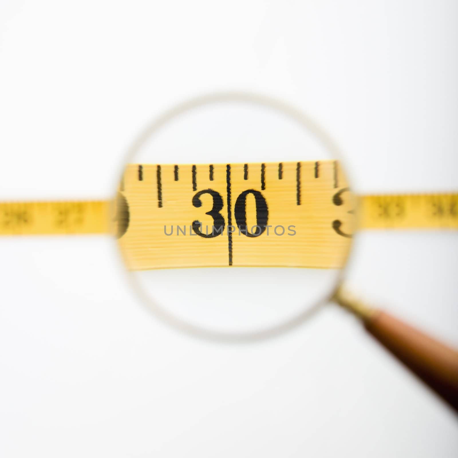 Magnifying glass held over measuring tape.