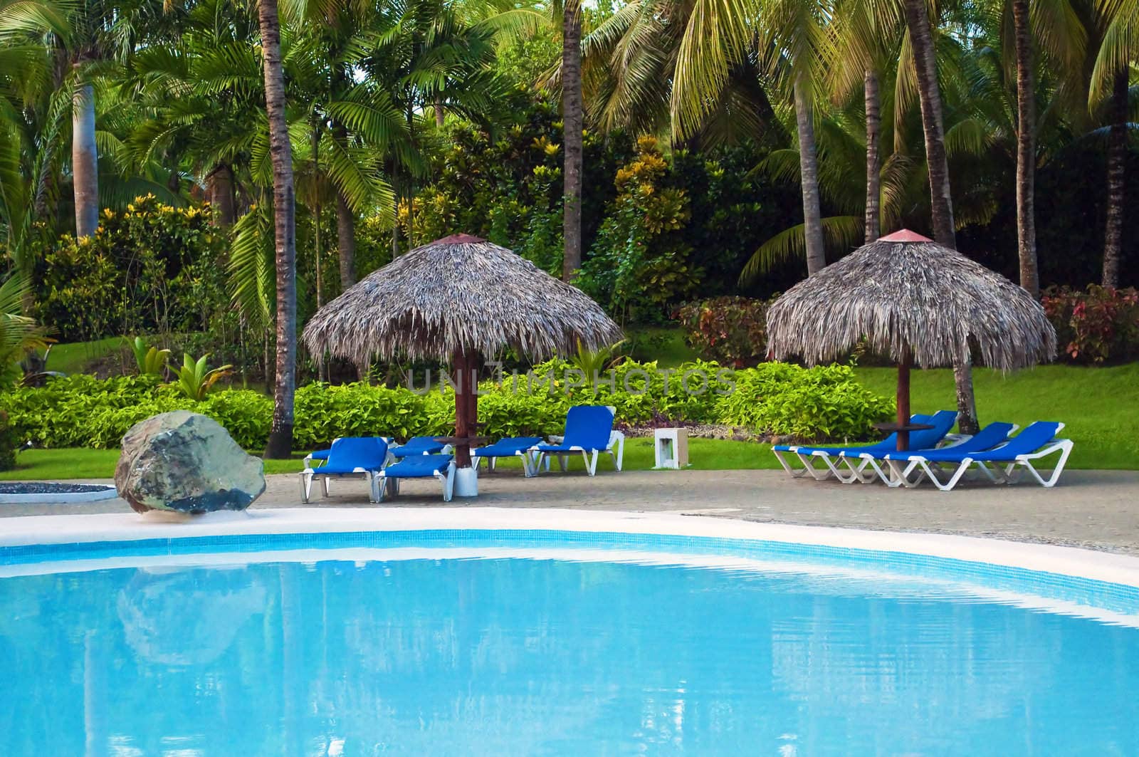 Huts and sunbed by the pool at Caribbean holiday resort.