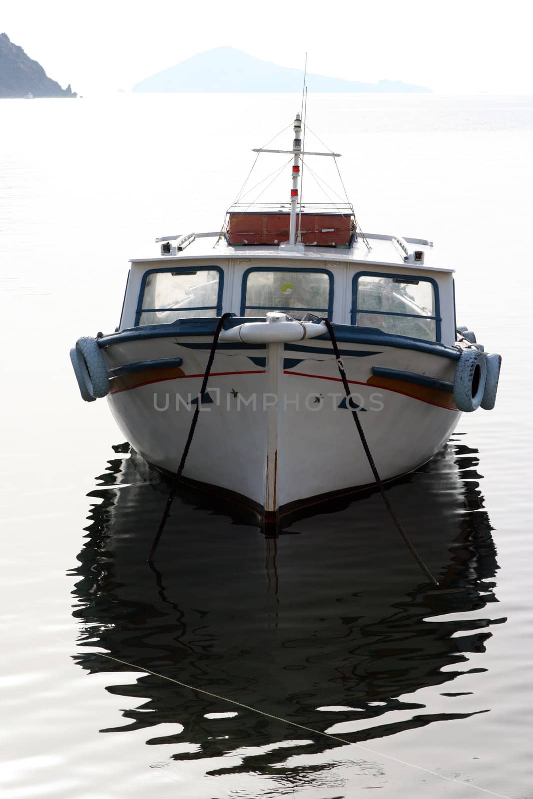 small wooden fishing boat anchored in sunset