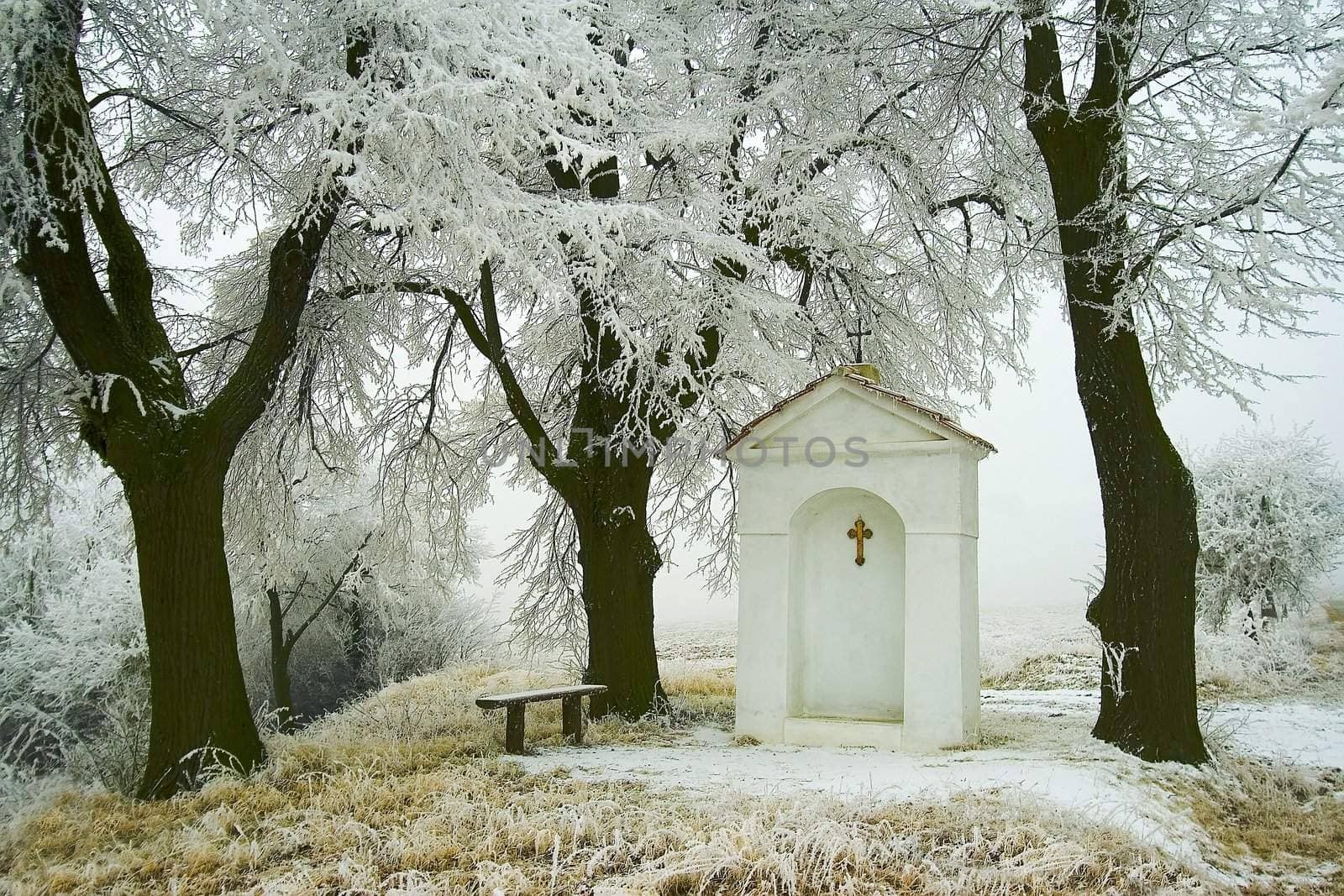 snowy winter landscape with a village chapel 