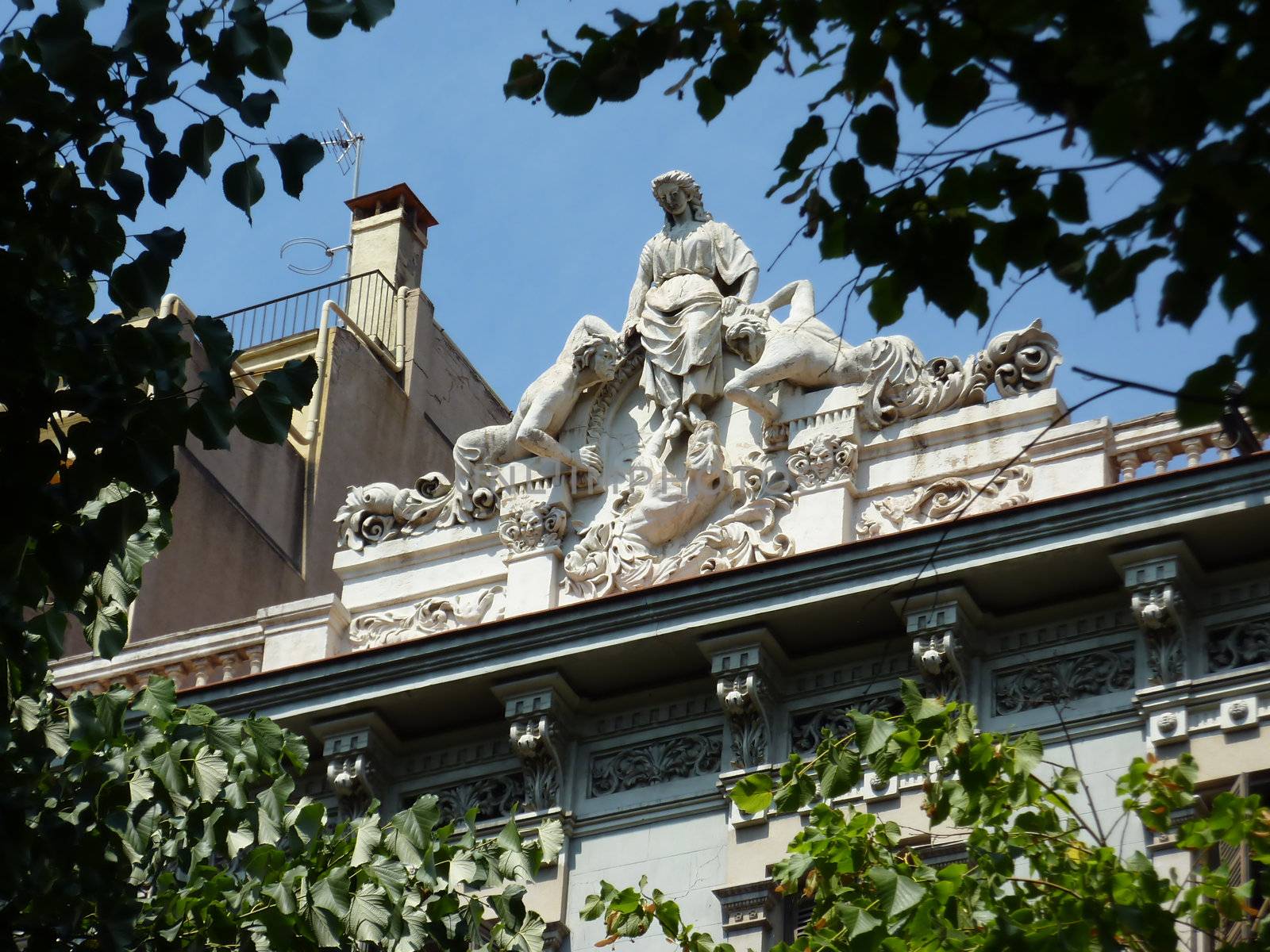 Sculpture of a woman and two men sirens on the top of a roof