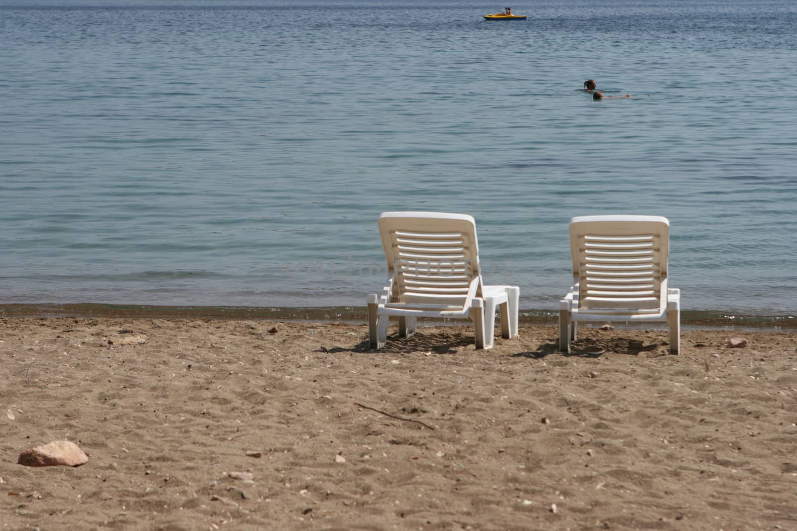 people swimming and two sunbeds by the sea patmos island greece
