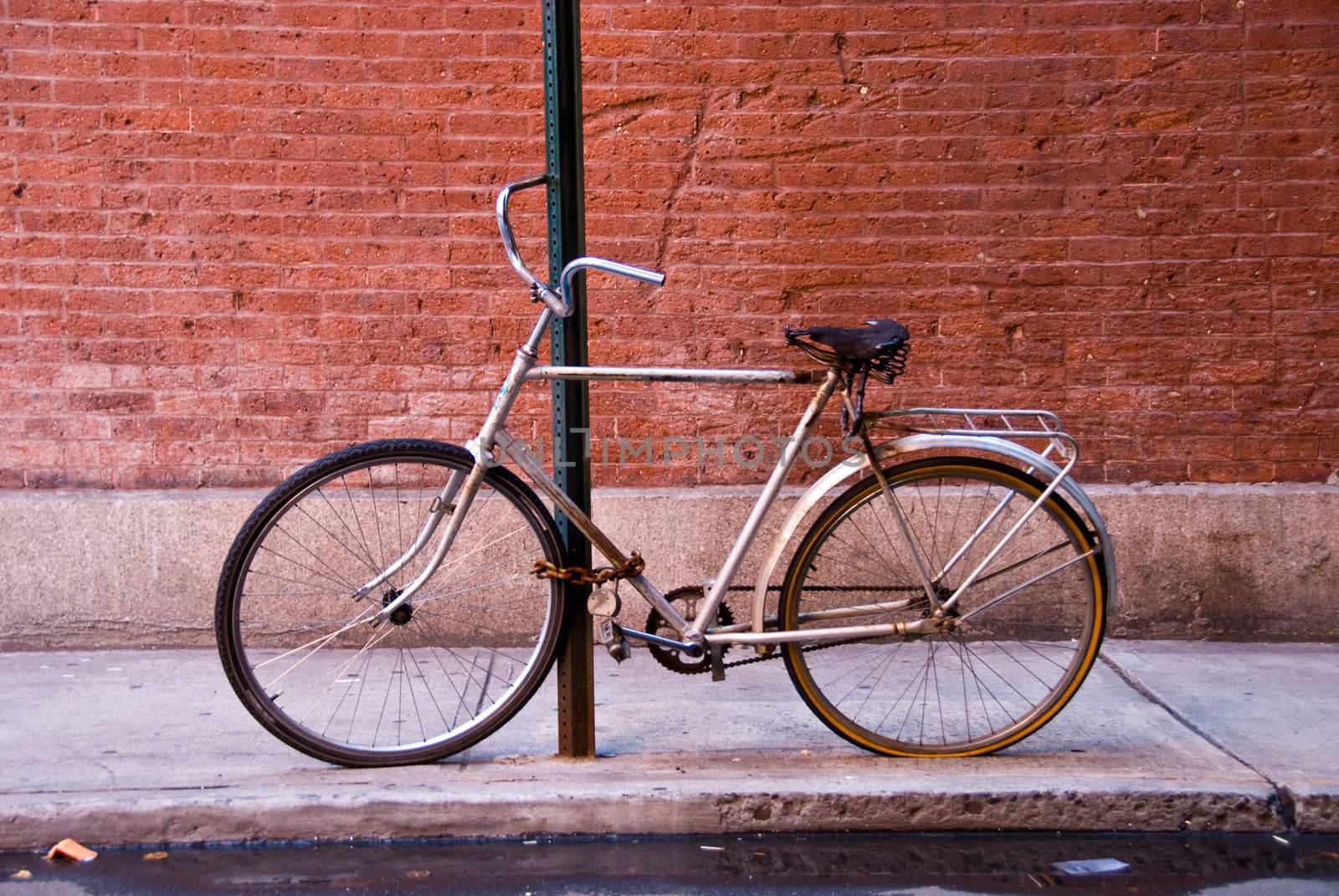 bicycle locked to post, brick wall behind by rongreer