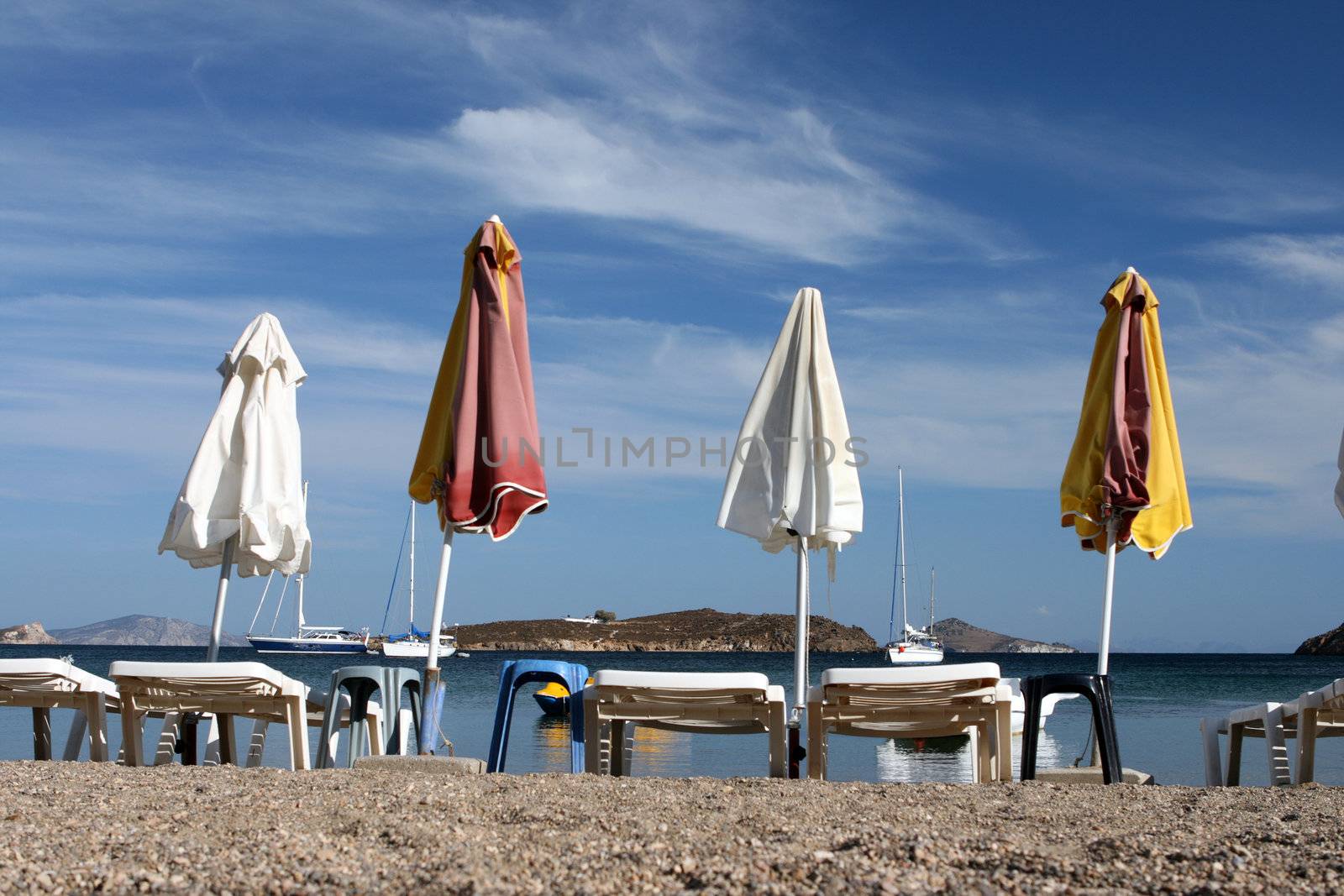 empty beach chairs and umbrellas and cloudy blue sky copyspace