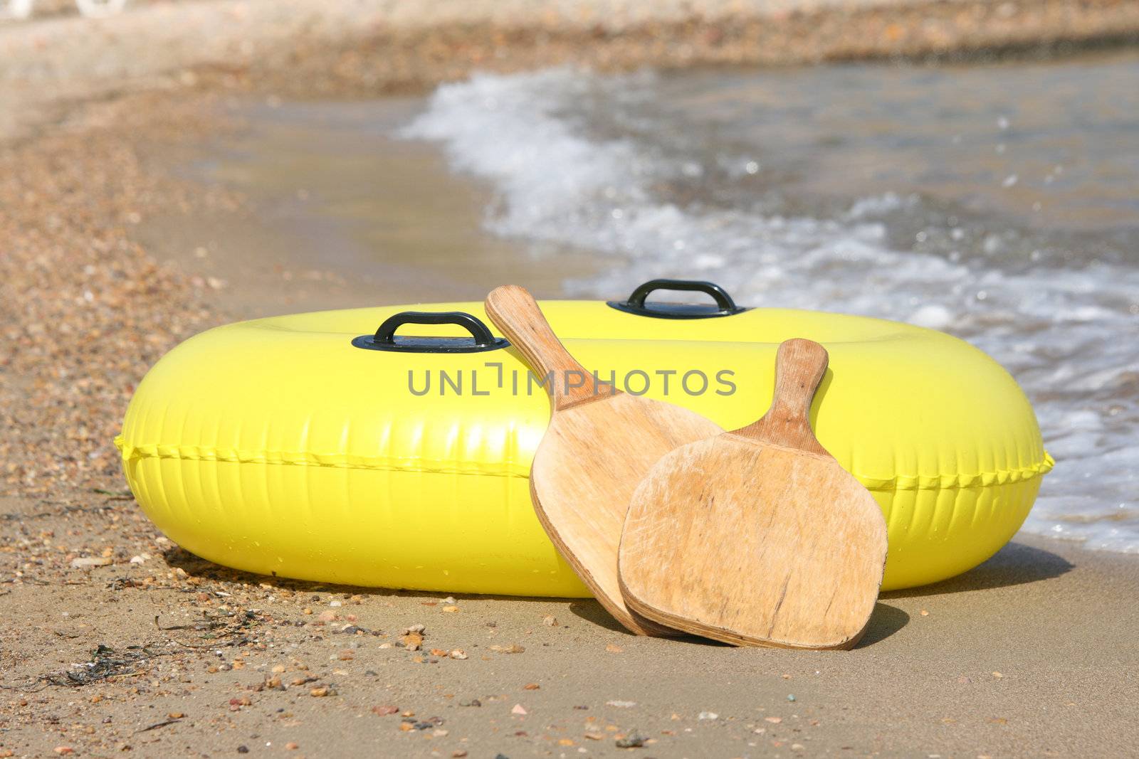 yellow Inflatable  Ring by the sea and wooden beach tennis rackets