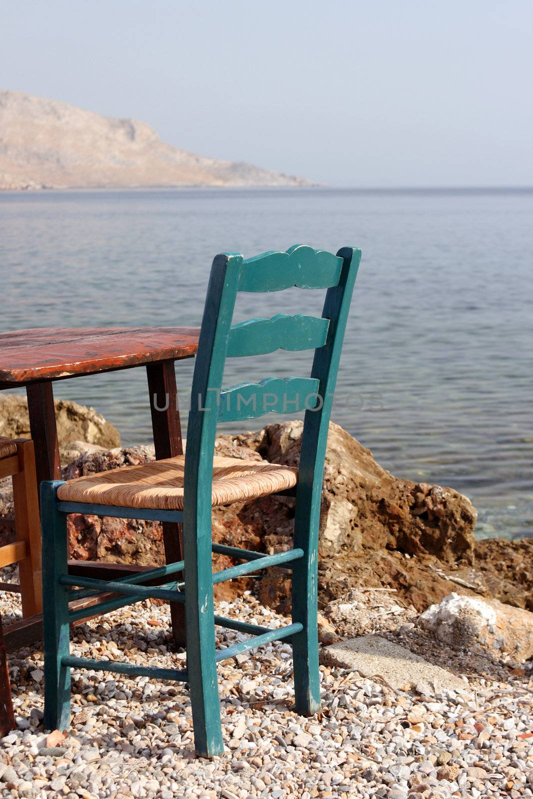 old green chair by the sea detail from greek taverna leros island greece