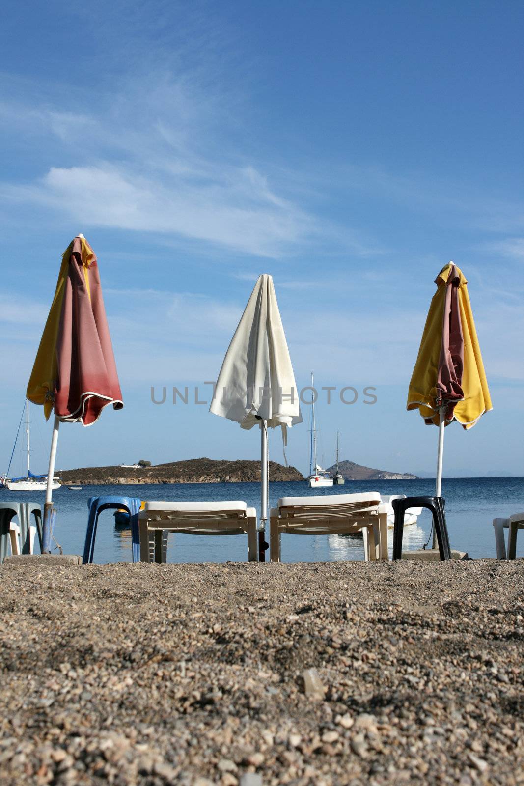 empty beach chairs and umbrellas and cloudy blue sky copyspace