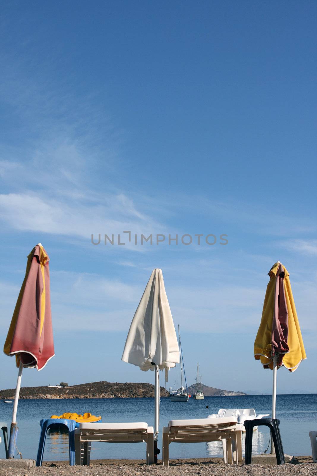 empty beach chairs and umbrellas and cloudy blue sky copyspace