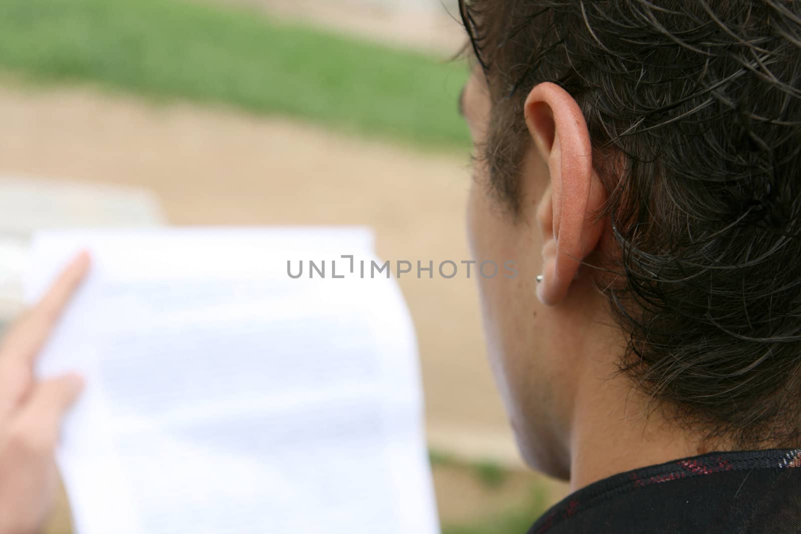 young man reading a document outdoors 