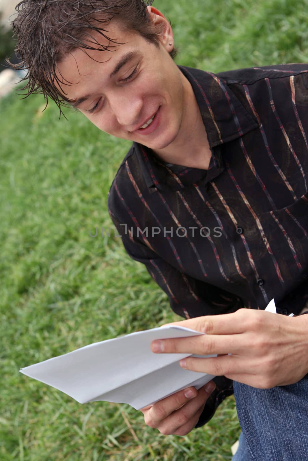 young student reading a document outdoors some good news and smile