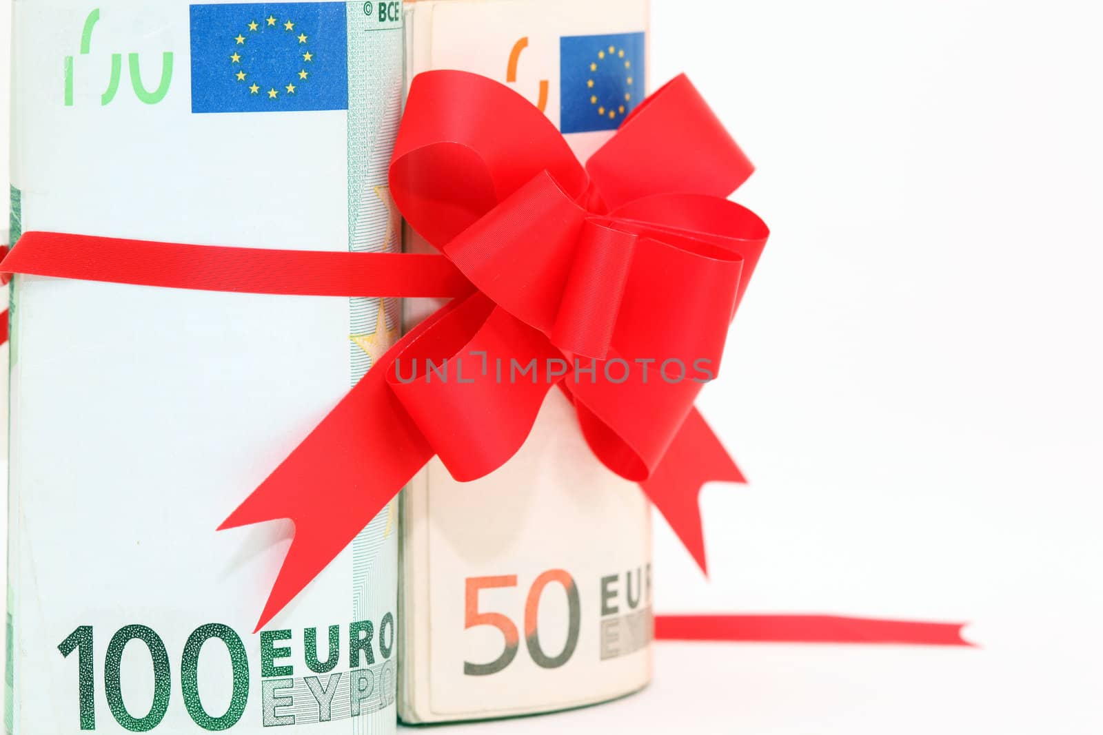 closeup rolled euro banknotes fifty and hundred with red ribbon