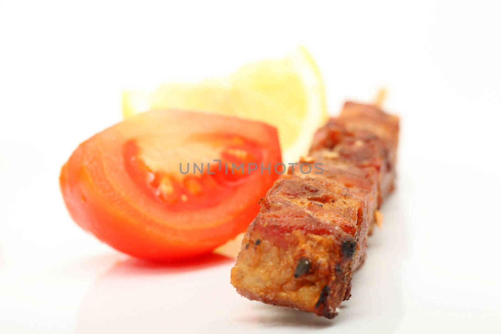 pork kebap on wooden stick grilled isolated with tomato and lemon