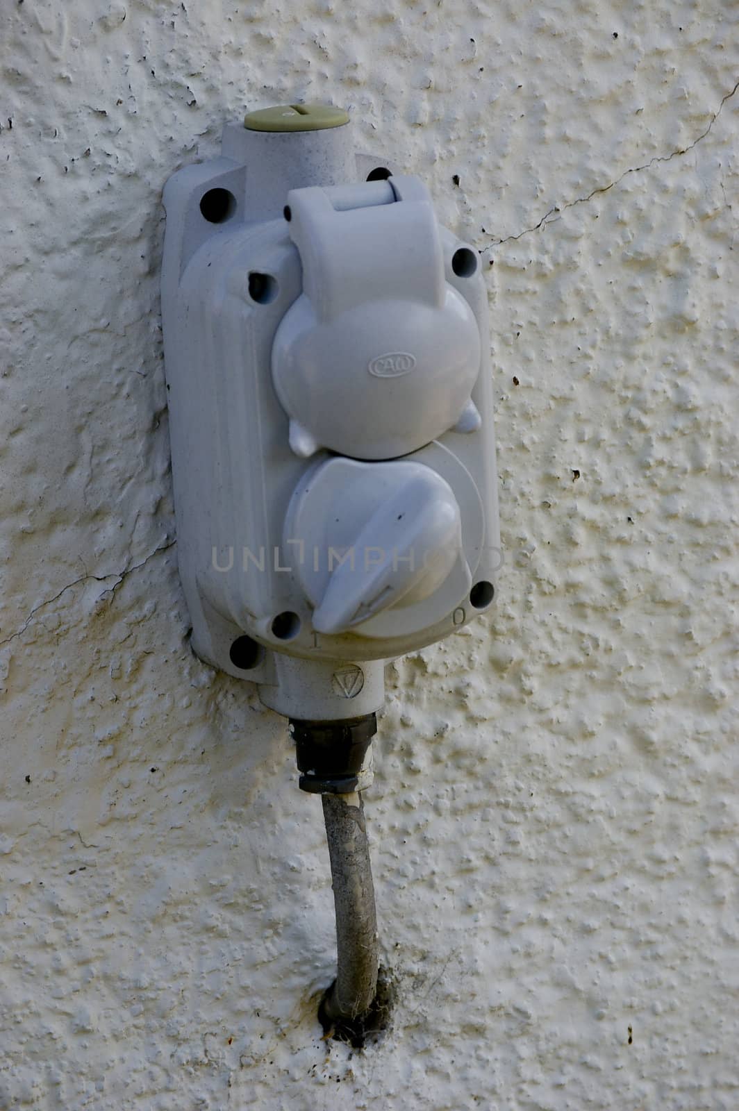 An old electrical socket with a switch. mounted on a white wall.