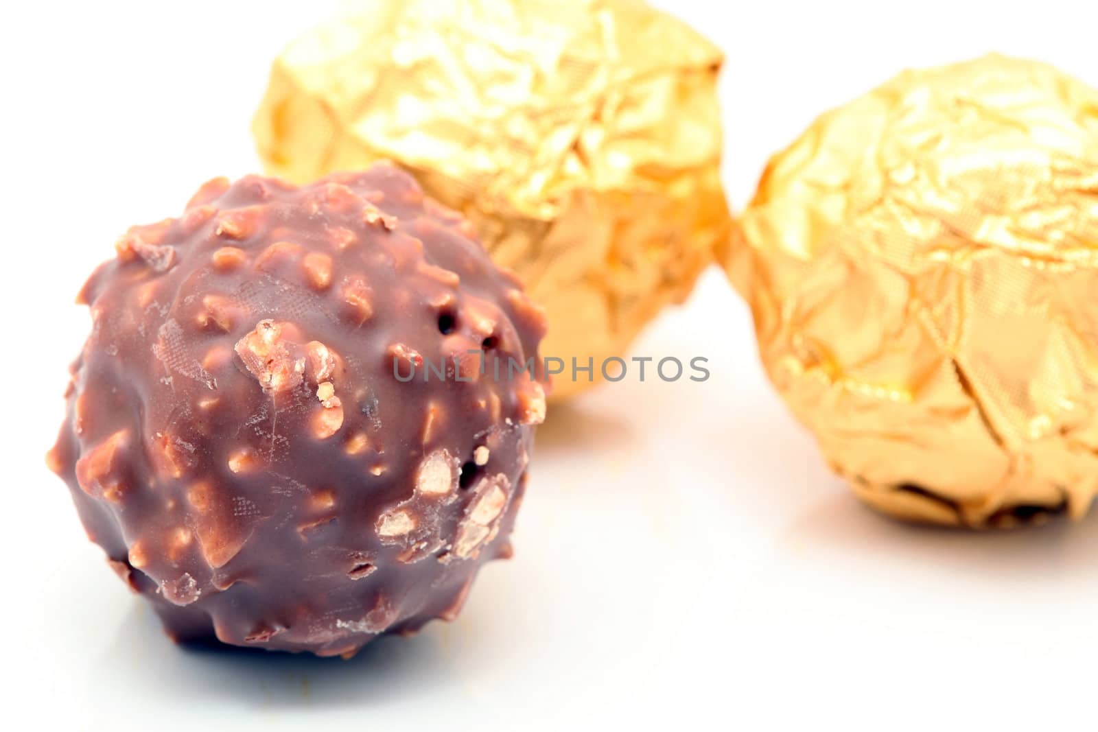 closeup chocolate sphere with nuts with gold wraped defocus background