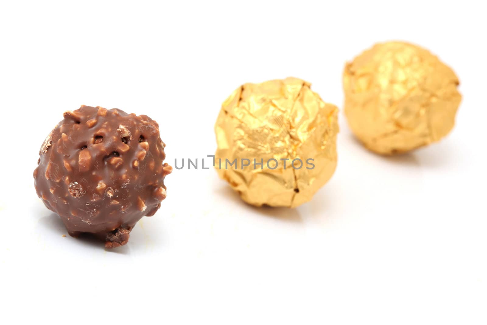 closeup chocolate sphere with nuts with two gold wraped isolated on  white background