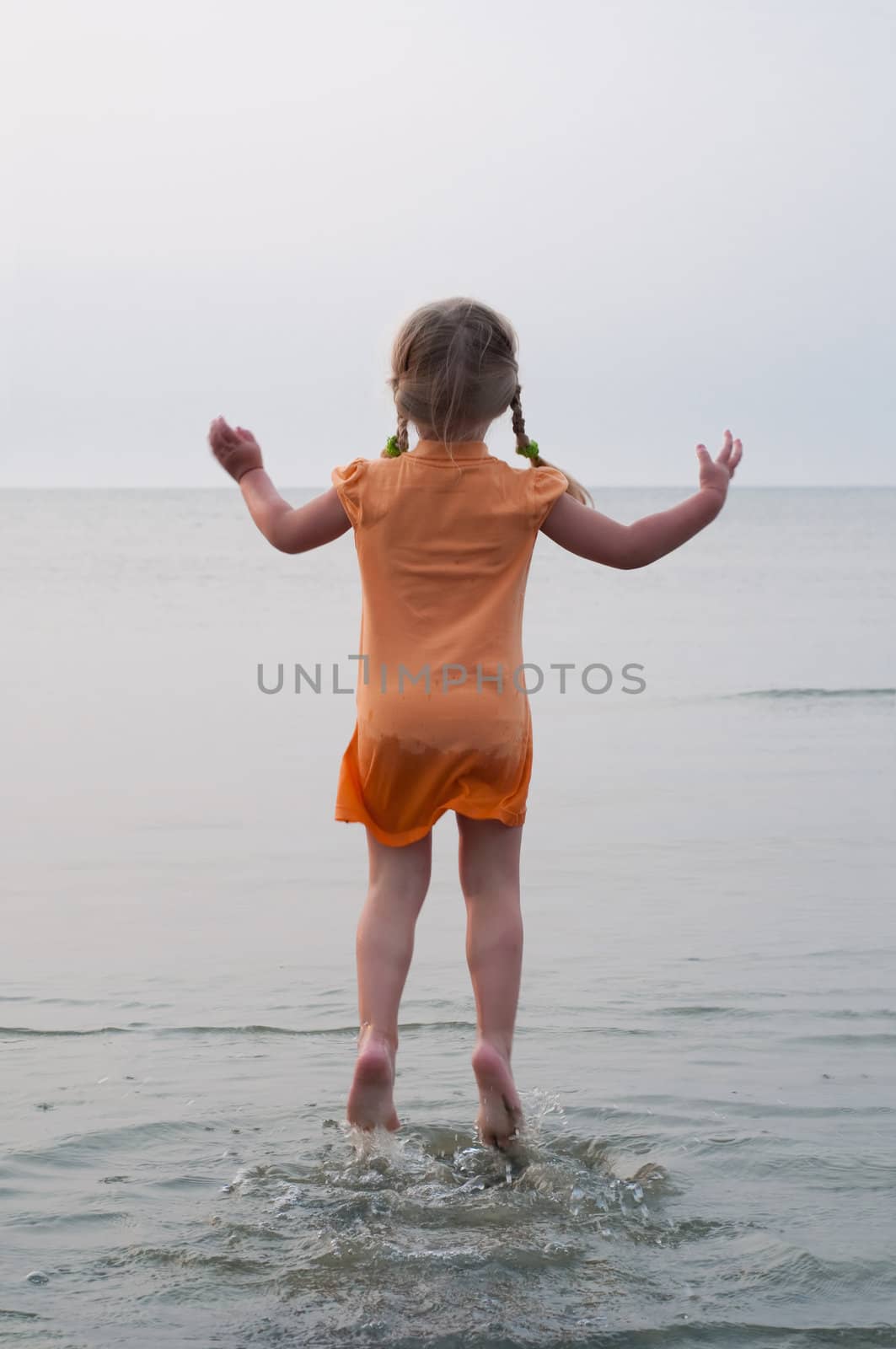 Little girl jumping on the sea, nature