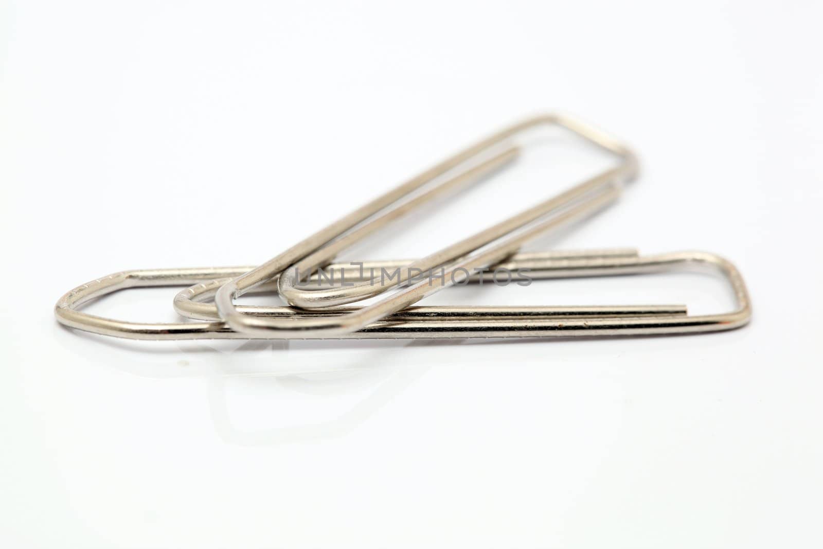 closeup two metallic paper clips isolated on white background