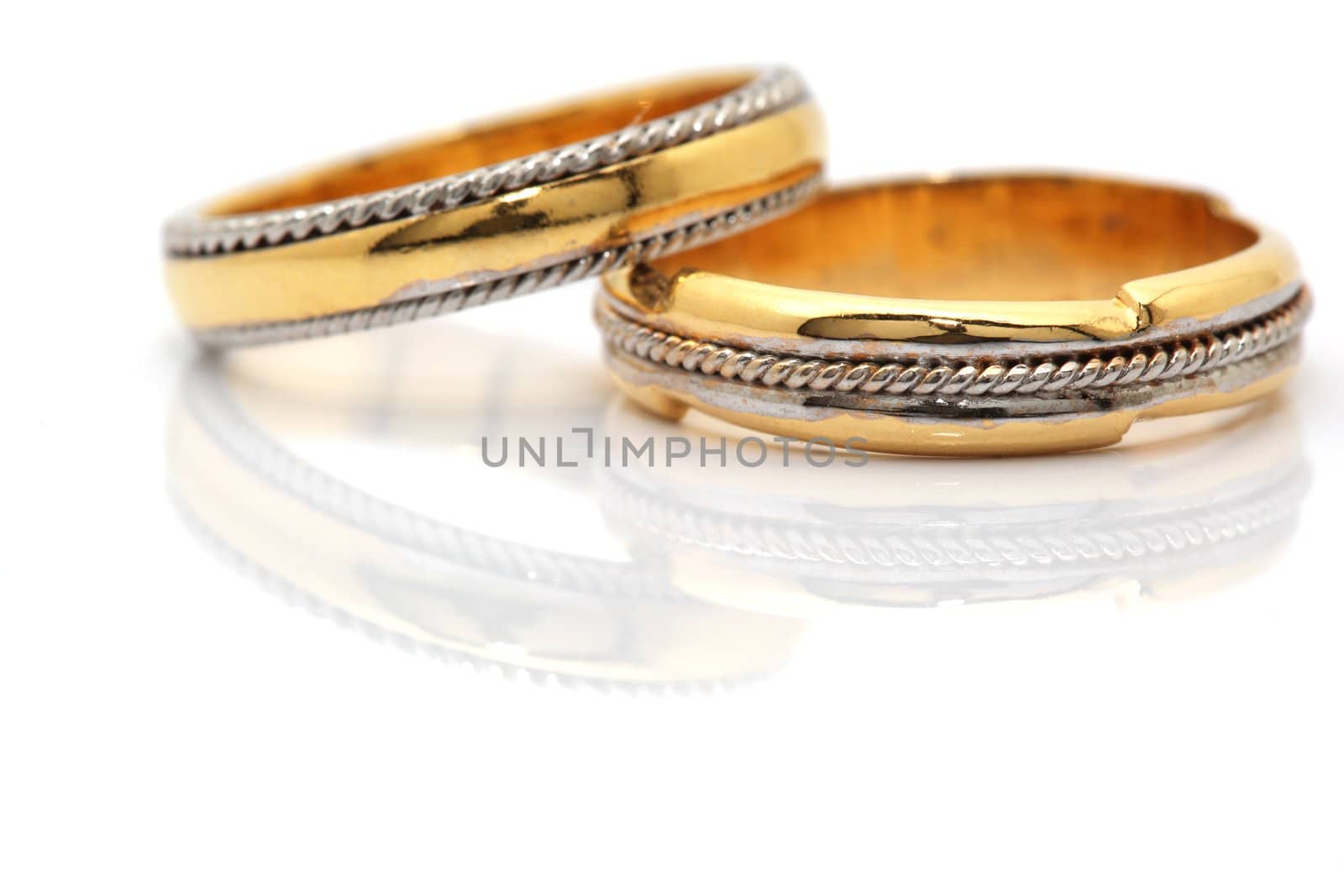 two gold wedding rings closeup reflected with copyspace on white
