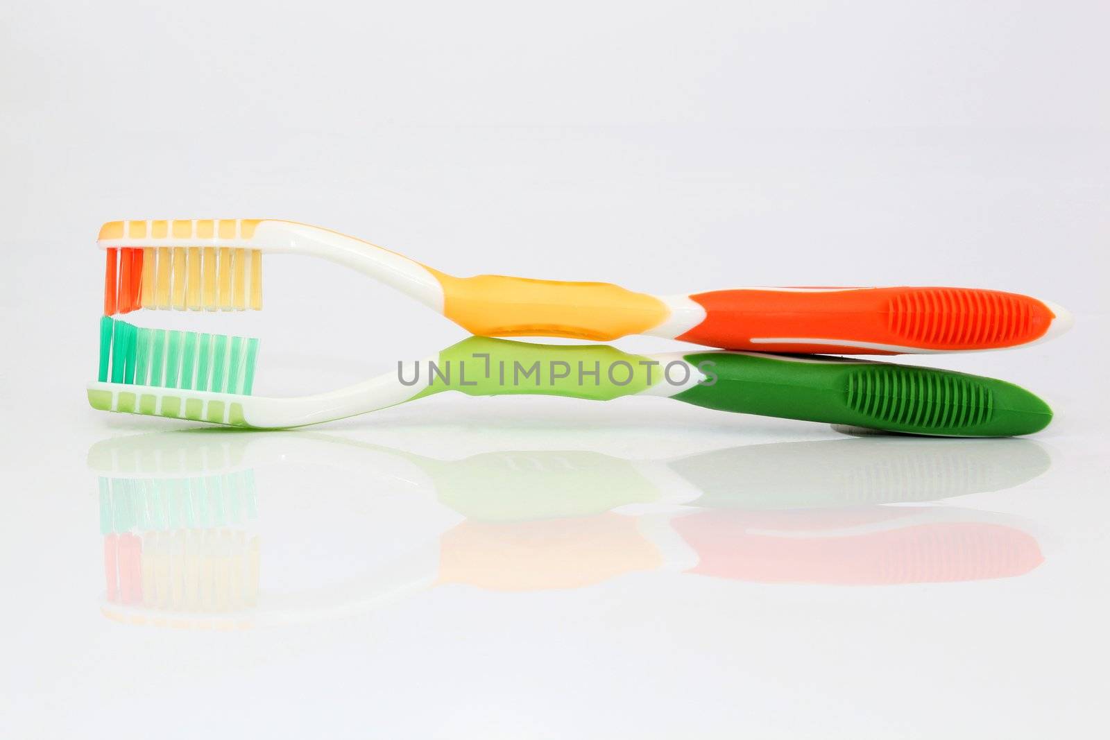 two color thoothbrushes on white background with reflection and copyspace