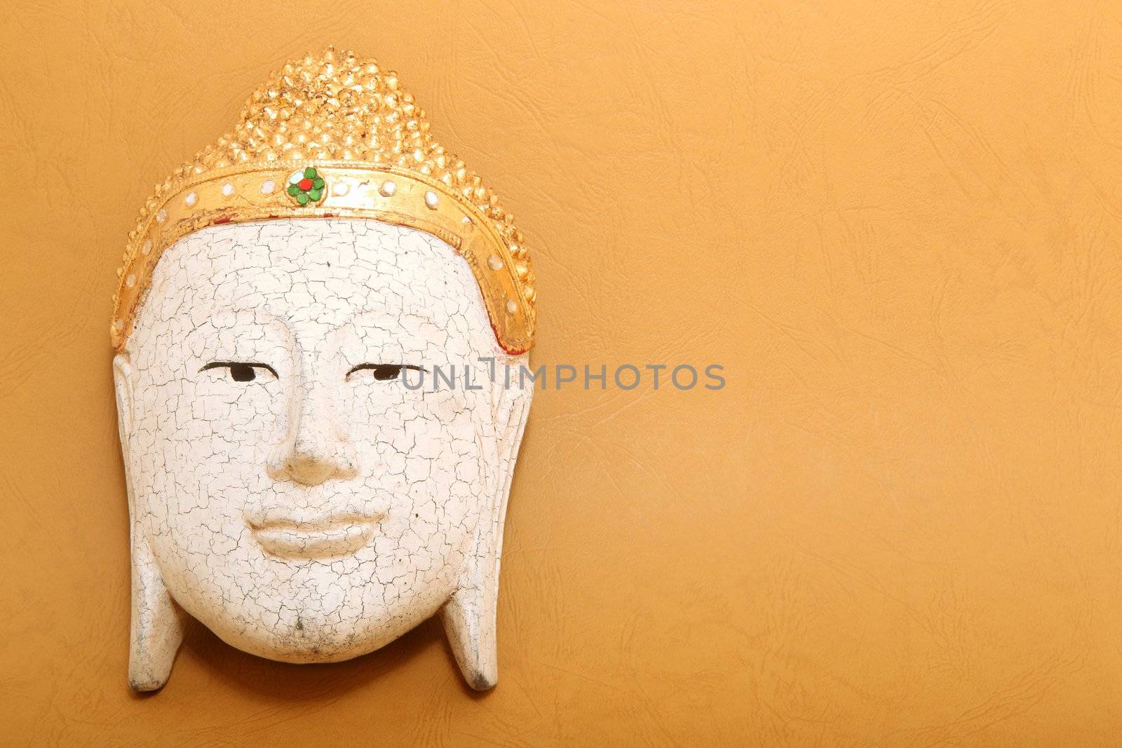 handcrafted wooden buddha decorative mask on yellow background with copyspace