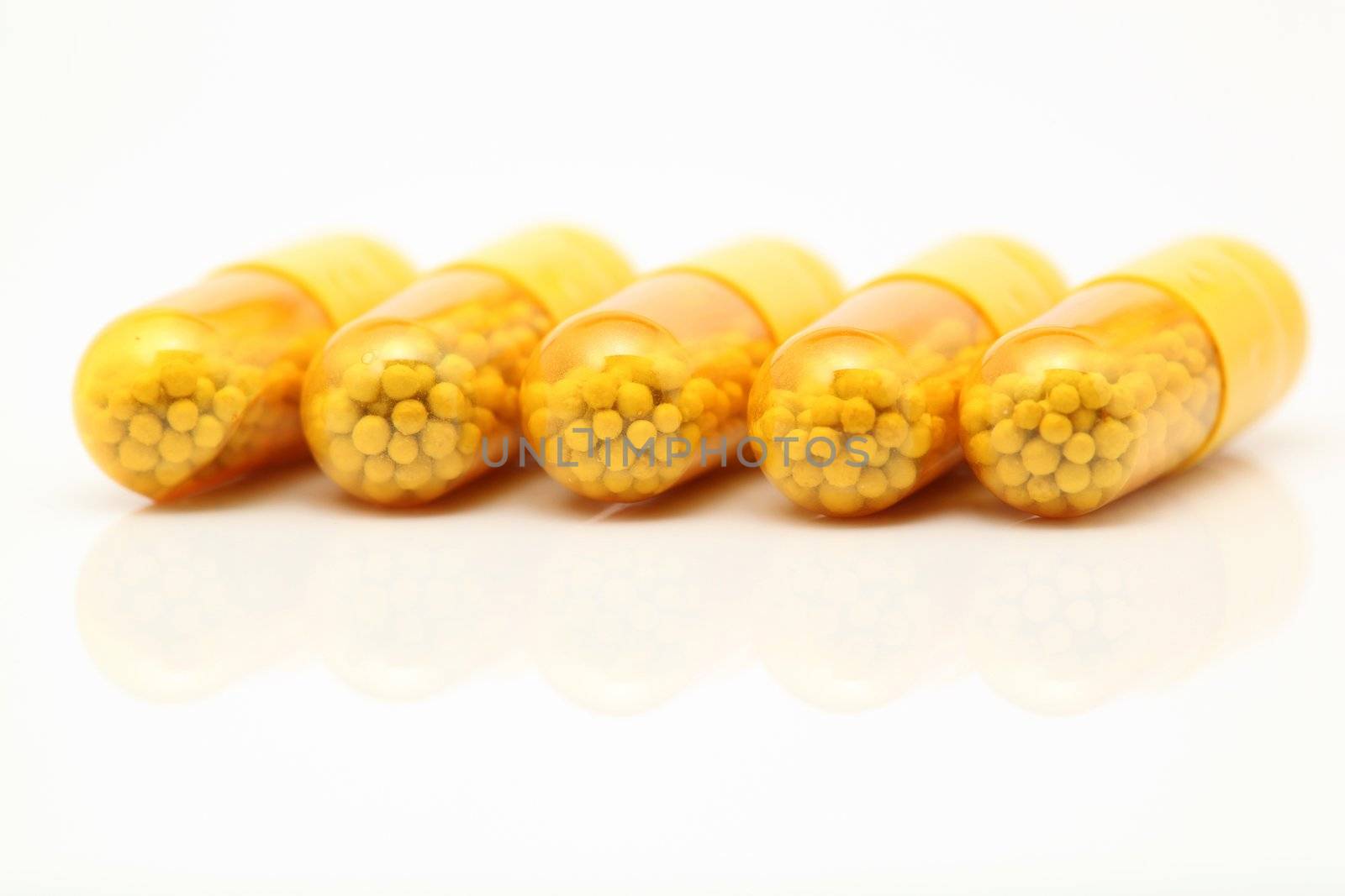 yellow medical capsules closeup detail with reflection on white background