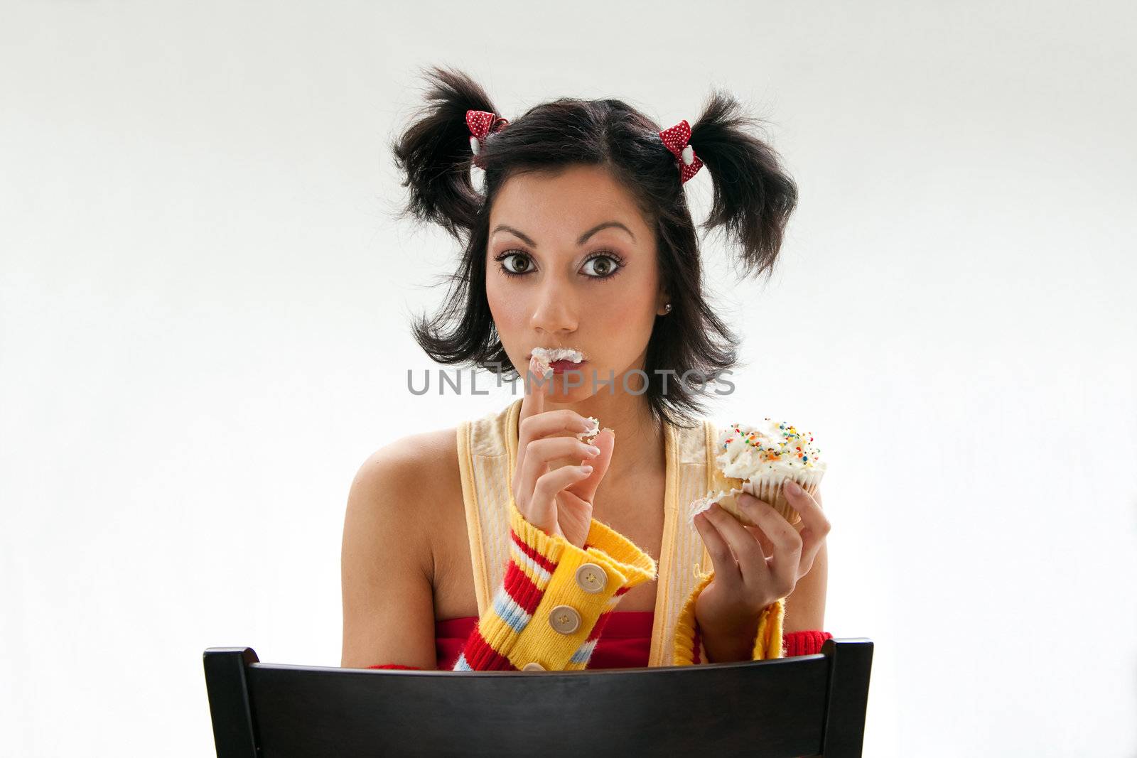 Beautiful Latina girl eating a cupcake with her fingers, isolated