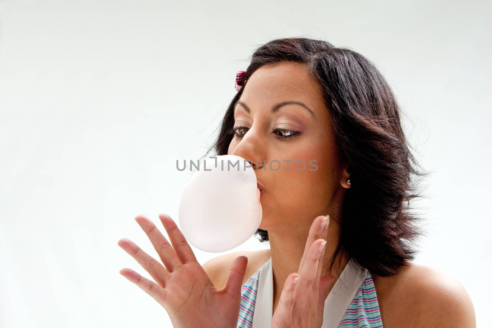 Beautiful Latina girl with crossed eyes blowing a bubblegum bubble, isolated