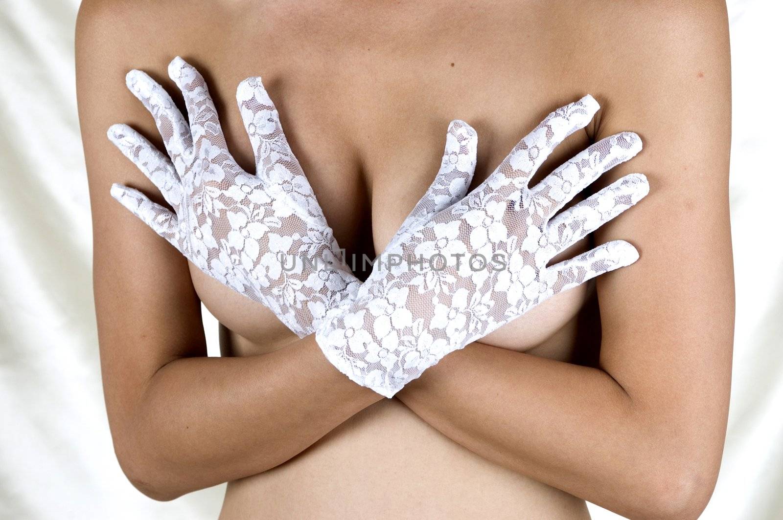 Erotic pose, seducing, shy girl covering her breasts with hands, putting sexy gloves.