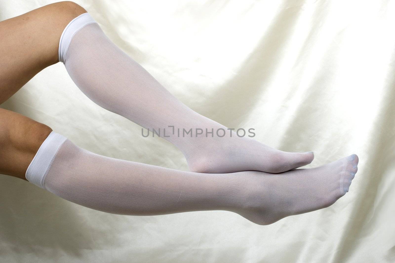Girl holding her legs up, sexy pose, seducing, putting short, white stockings.