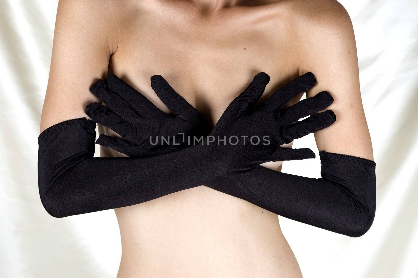 Erotic pose, seducing, shy girl covering her breasts with hands, putting sexy gloves.