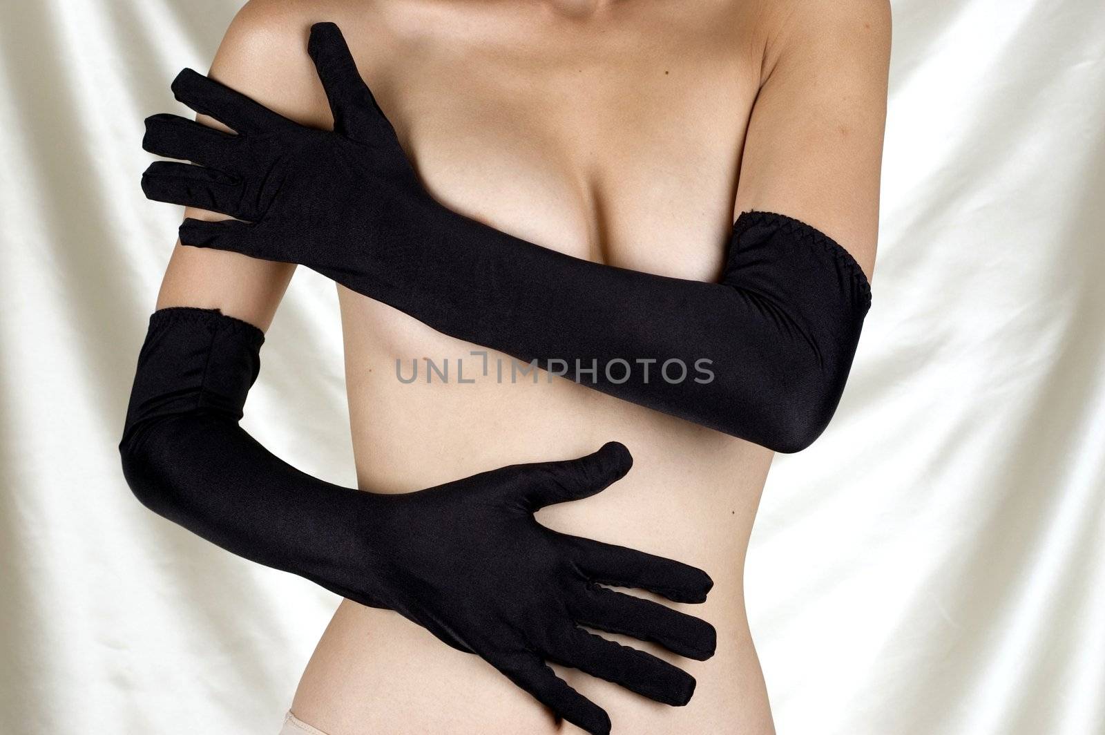 Erotic pose, seducing, shy girl covering her breasts with hands, putting sexy gloves.