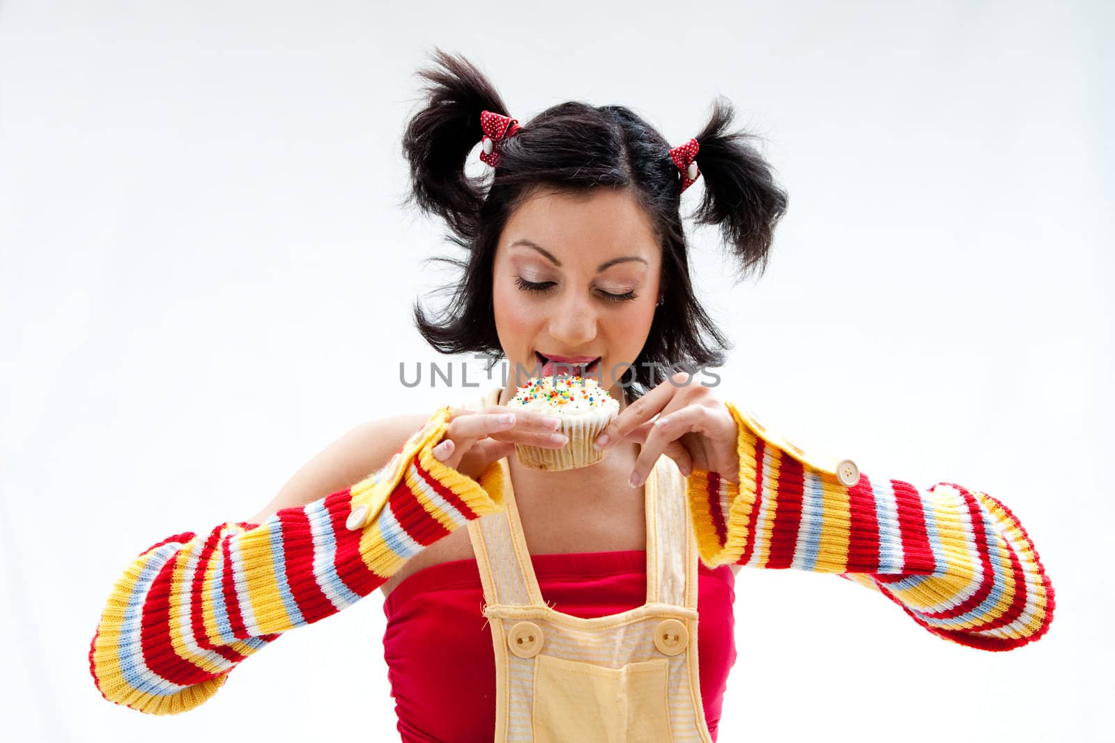 Beautiful Latina girl licking a cupcake, isolated