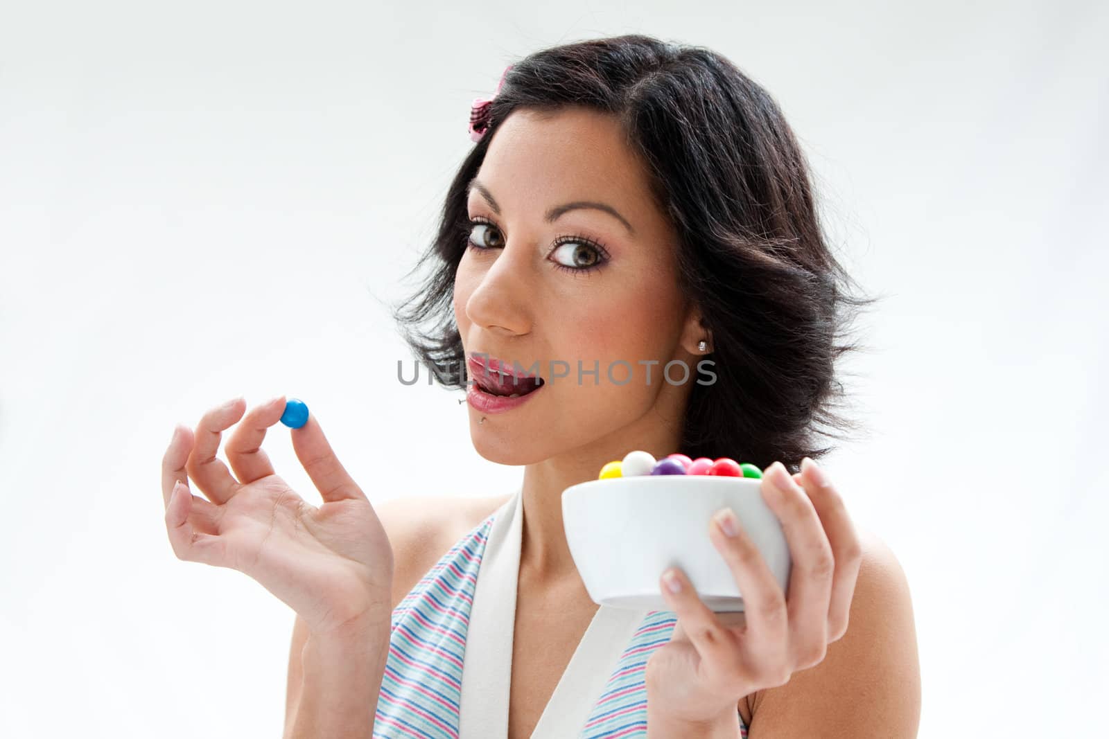 Happy beautiful candy girl with a bowl of colorful bubblegum candy balls licking her lip, isolated