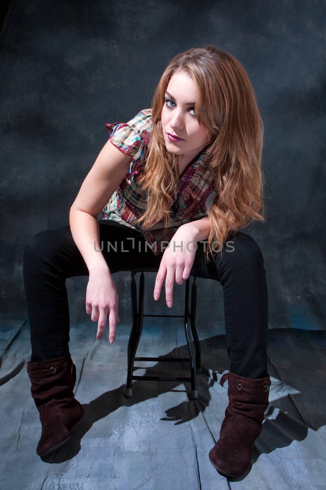 Beautiful dirty-blond girl sitting on stool with attitude