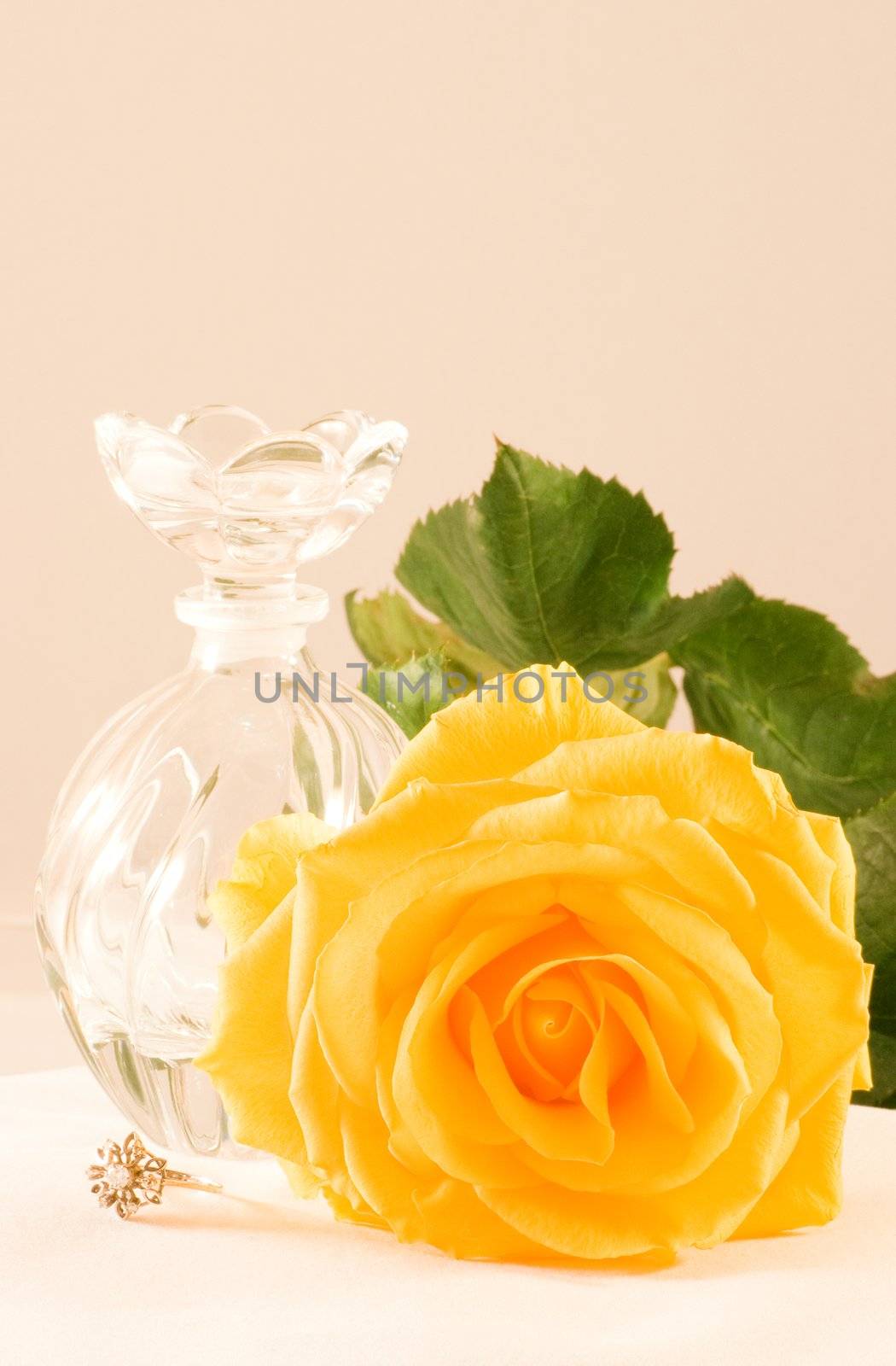 Yellow rose with green leaves, small glass bottle and diamond ring