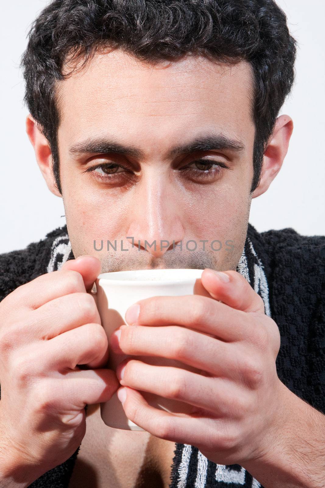 Tired handsome man with a mug wearing a black robe, isolated