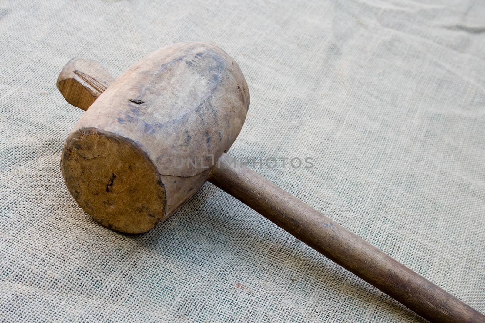 Old wooden mallet hammer on burlap background