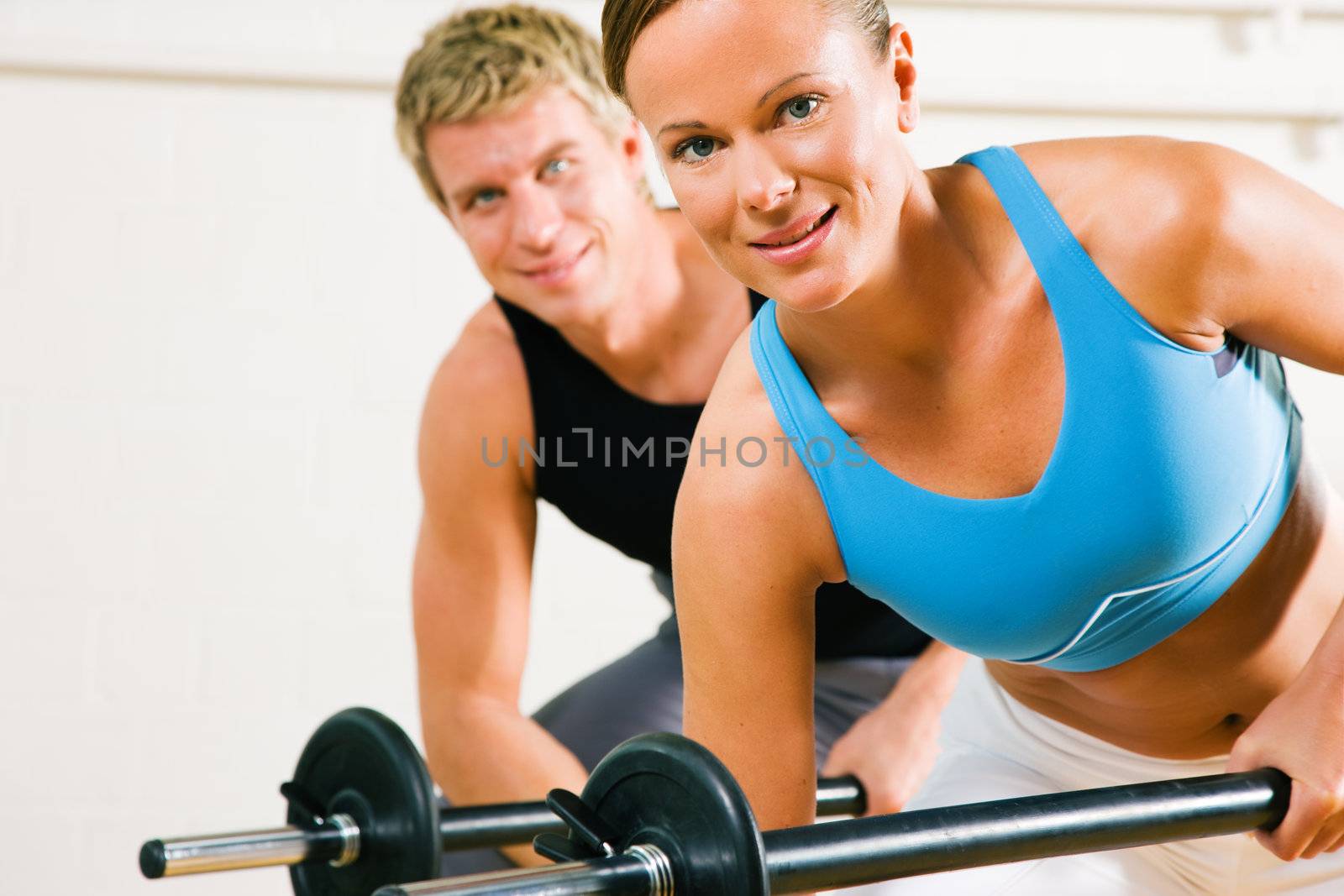 Very attractive and sportive couple doing power gymnastics with barbells